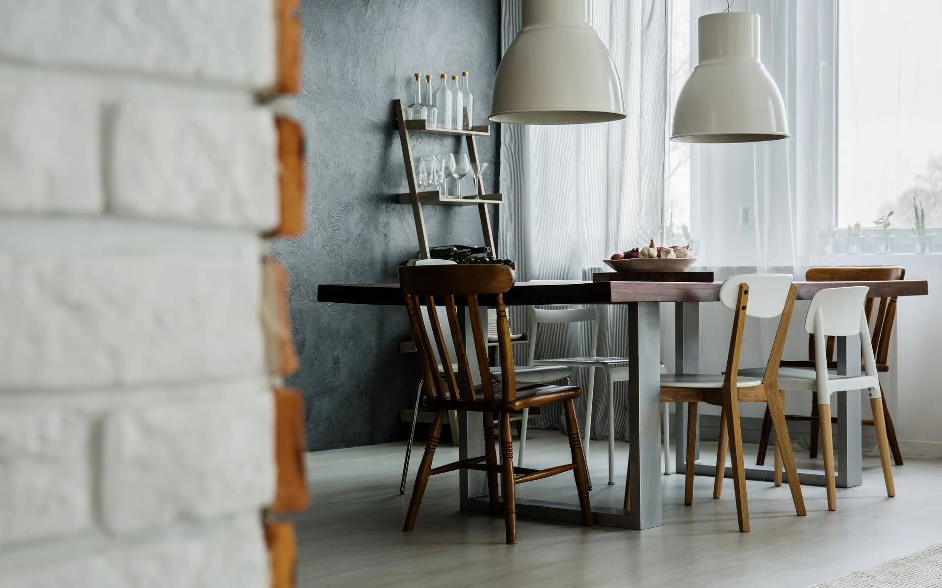 Cozy dining area with wooden chairs and pendant lights near a window.