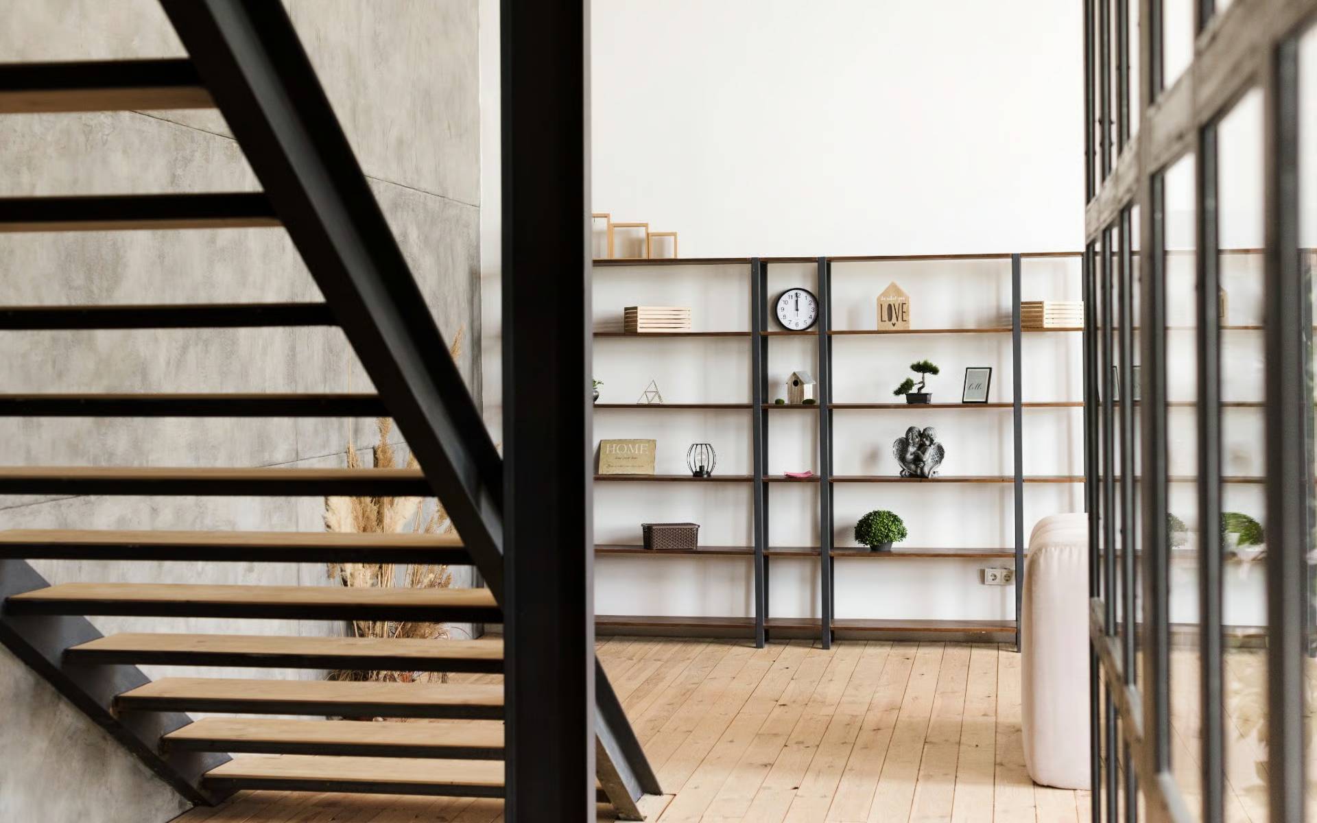 Minimalist interior with wooden shelves and a black staircase.