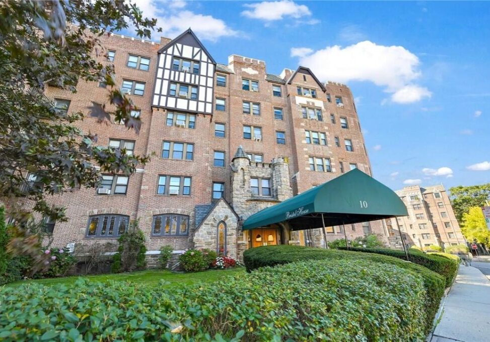 Historic brick apartment building with Tudor-style details and a green awning.