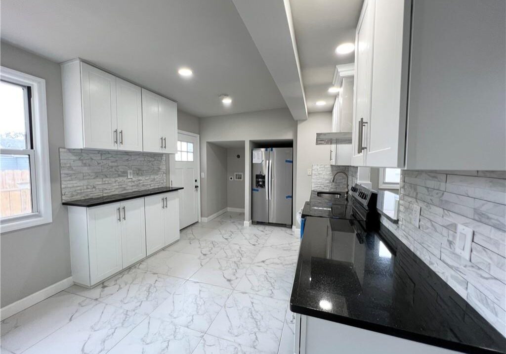 Modern kitchen with white cabinetry and black countertops.