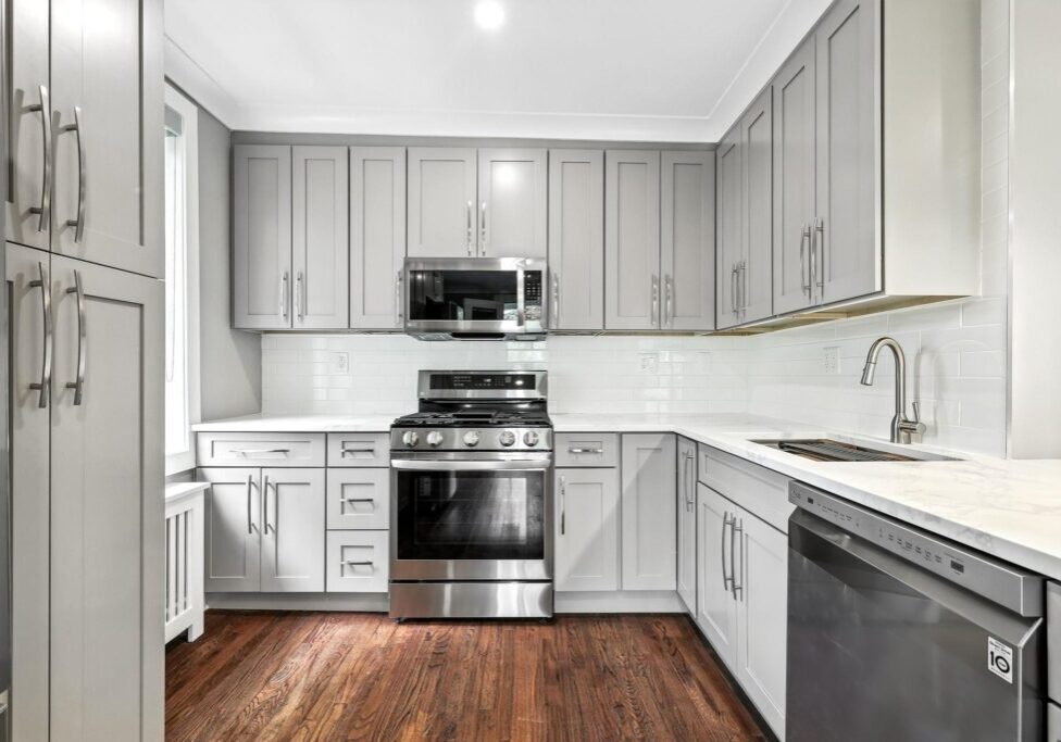 Modern kitchen with stainless steel appliances and wooden flooring.