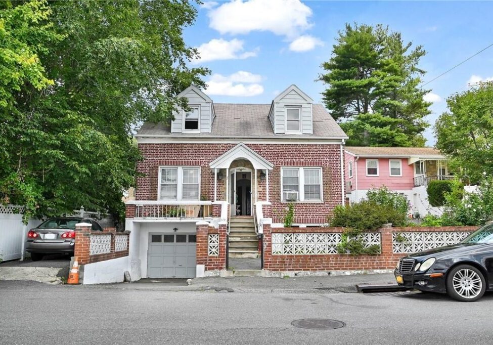 A brick two-story house with a garage and arched front entrance.