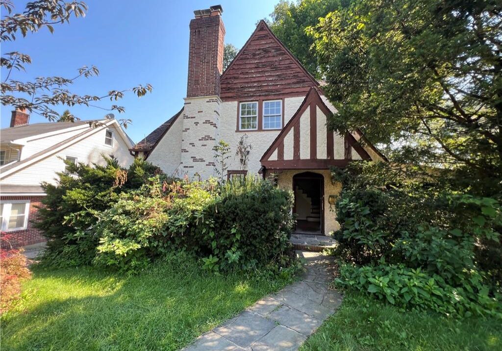 Charming Tudor-style house with a steep roof and lush greenery.