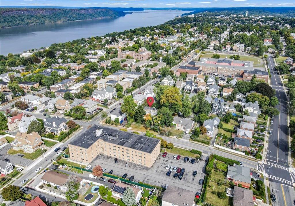 Aerial view of a suburban neighborhood near a river with houses and greenery.