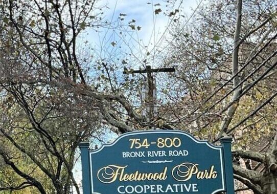 Welcome sign to Westwood Park Cooperative under tree branches.