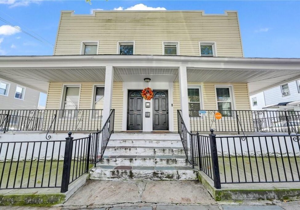 Historic building with a front porch and stairs under a clear blue sky.