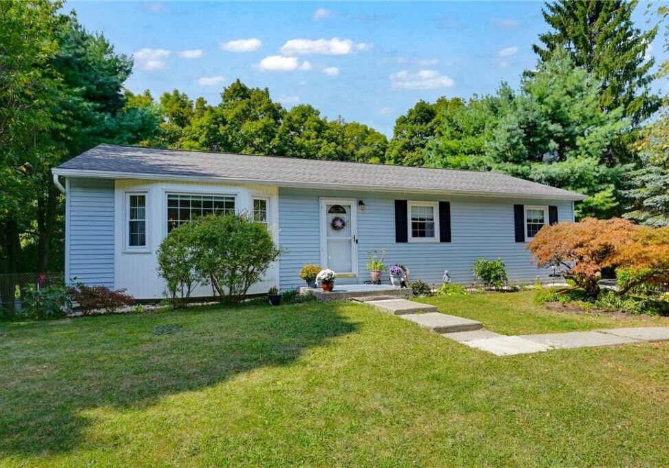 A white single-story house with a well-maintained lawn and greenery.