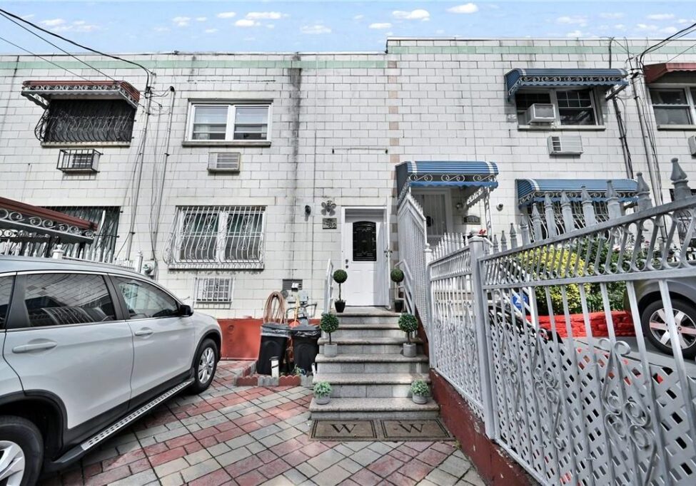 Two children sitting outside a white residential building with stairs.