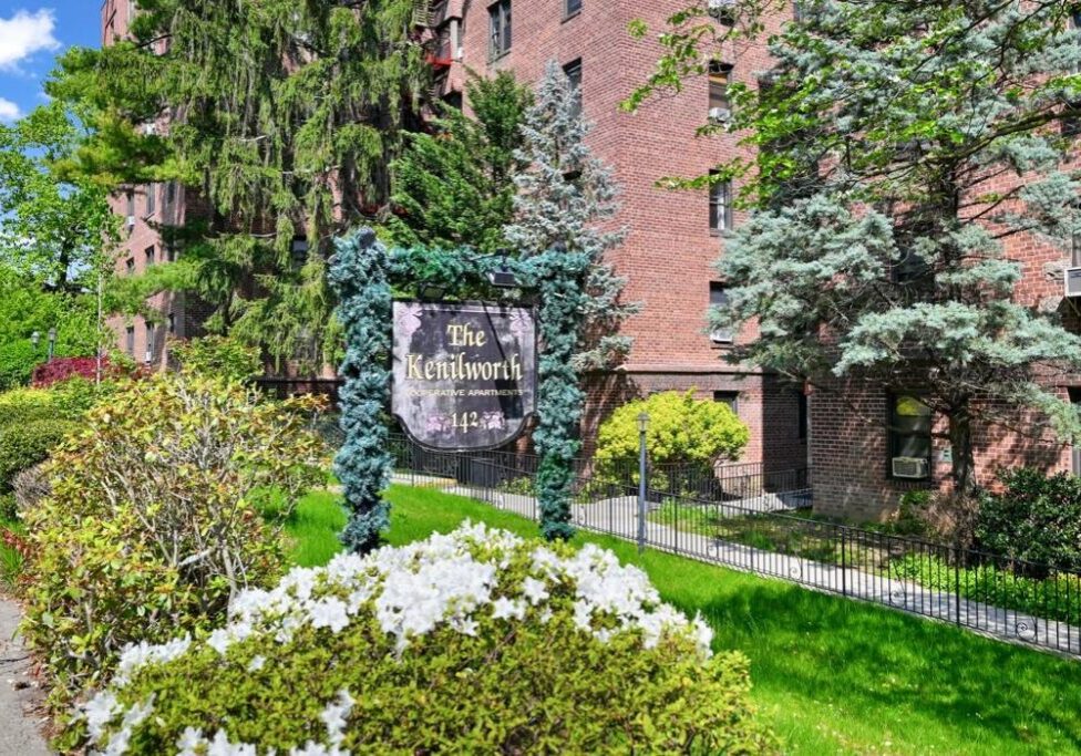 Entrance sign for The Birch Apartments surrounded by greenery.