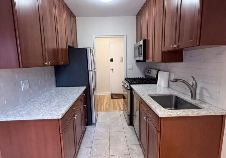 Modern kitchen with wooden cabinets and tiled floor.