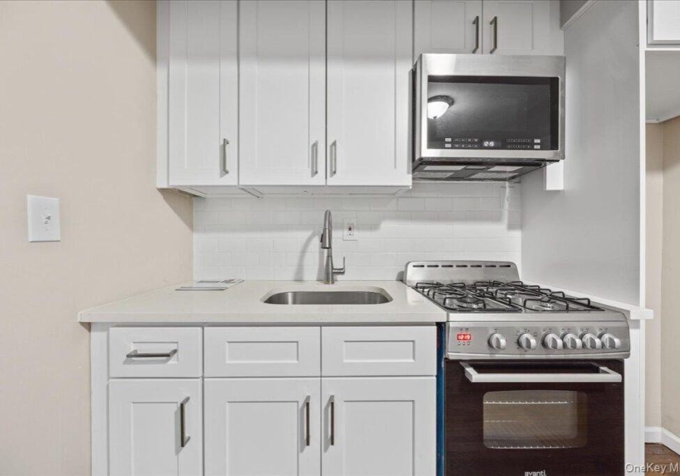 Modern white kitchen with stainless steel appliances and sleek cabinetry.