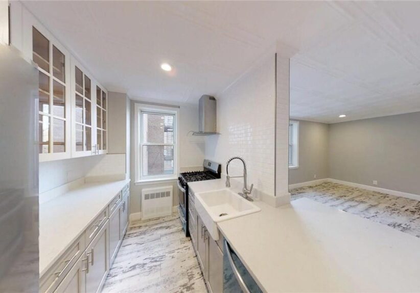 Bright modern kitchen with white cabinetry and marble flooring.