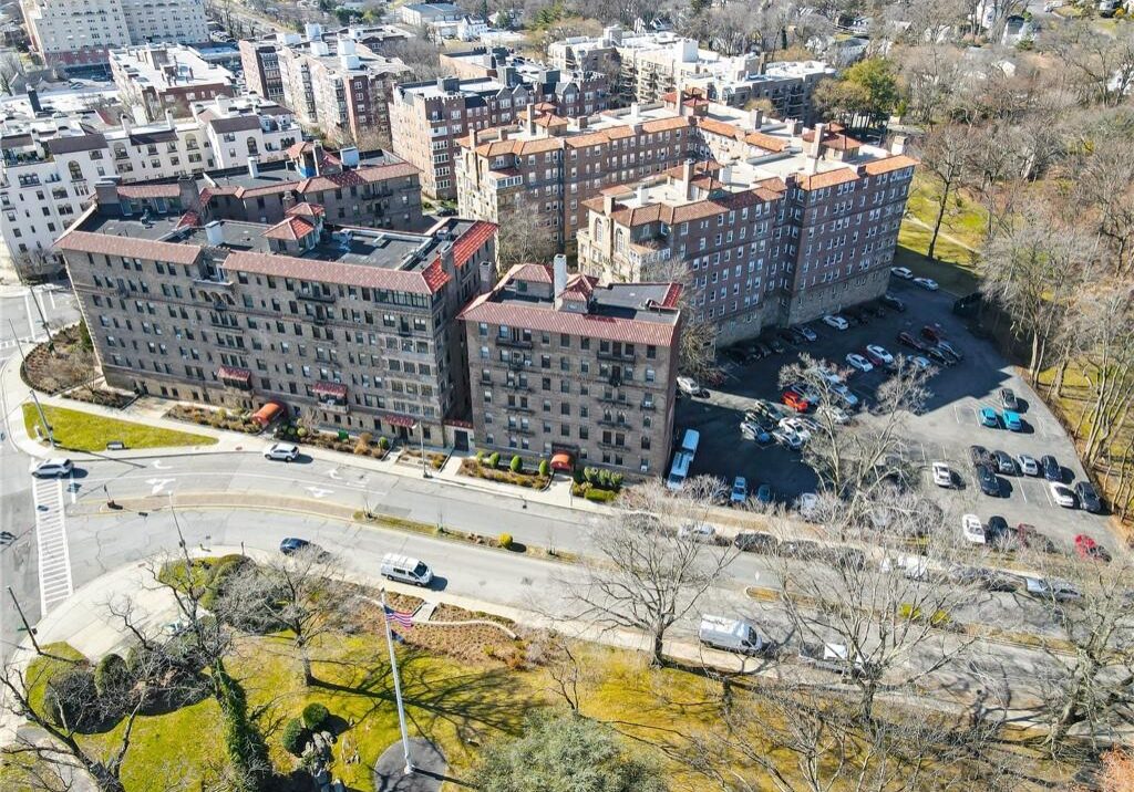 Aerial view of a city block with buildings, roads, and parked cars.