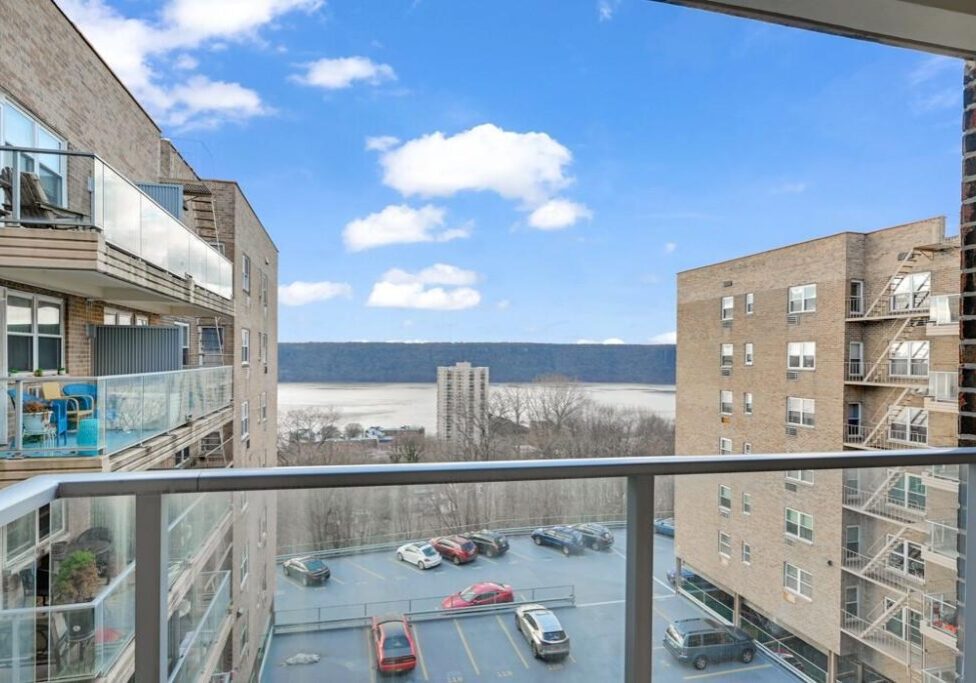 View of a parking lot and ocean from a balcony between two buildings.