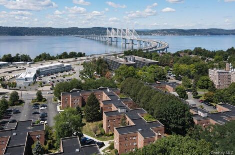 A large suspension bridge spanning over a river with nearby residential buildings.