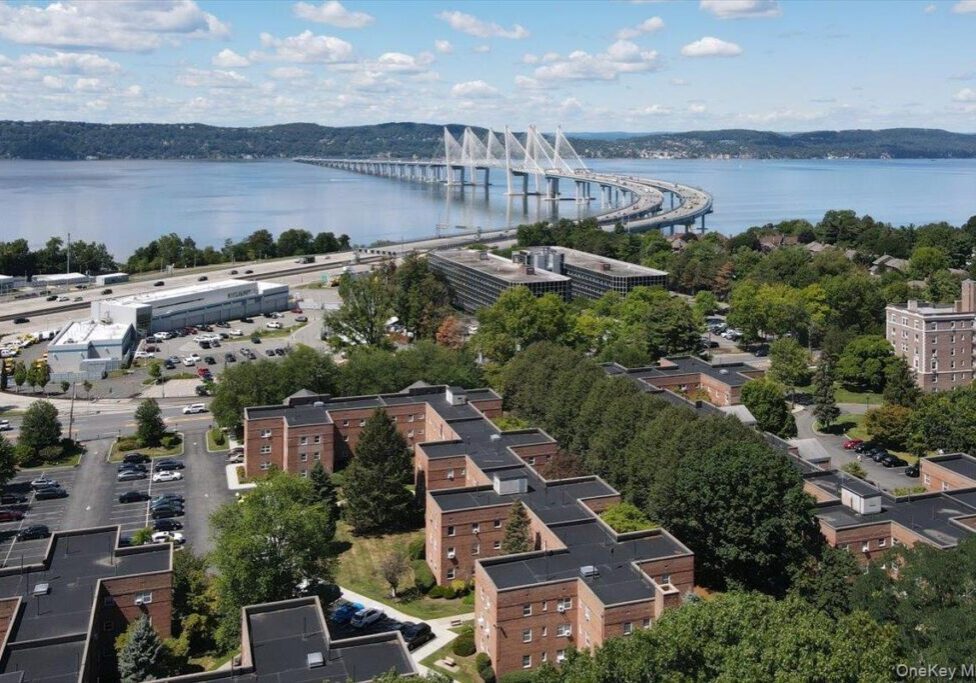 A large suspension bridge over a body of water with residential buildings in the foreground.