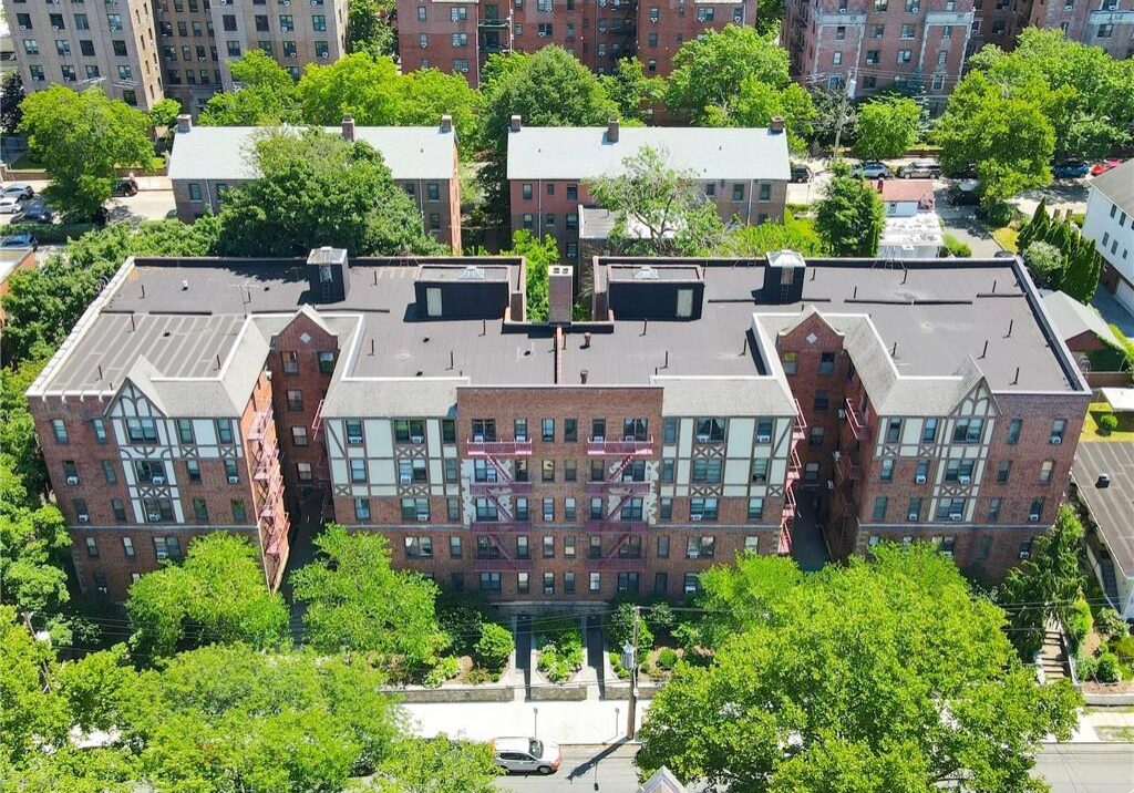 Aerial view of a brick apartment building surrounded by trees and greenery.