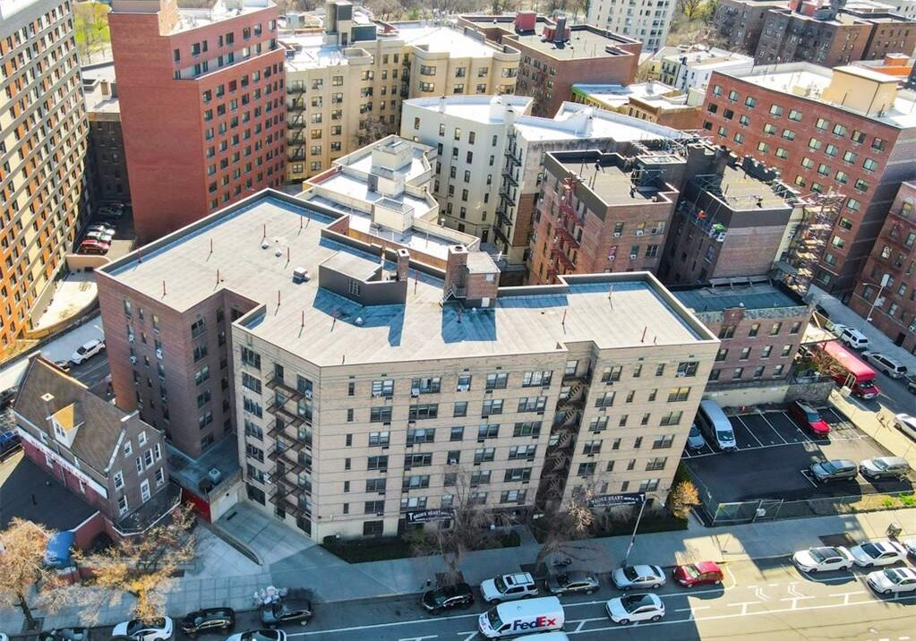 Aerial view of a city block with a large residential building and busy street below.