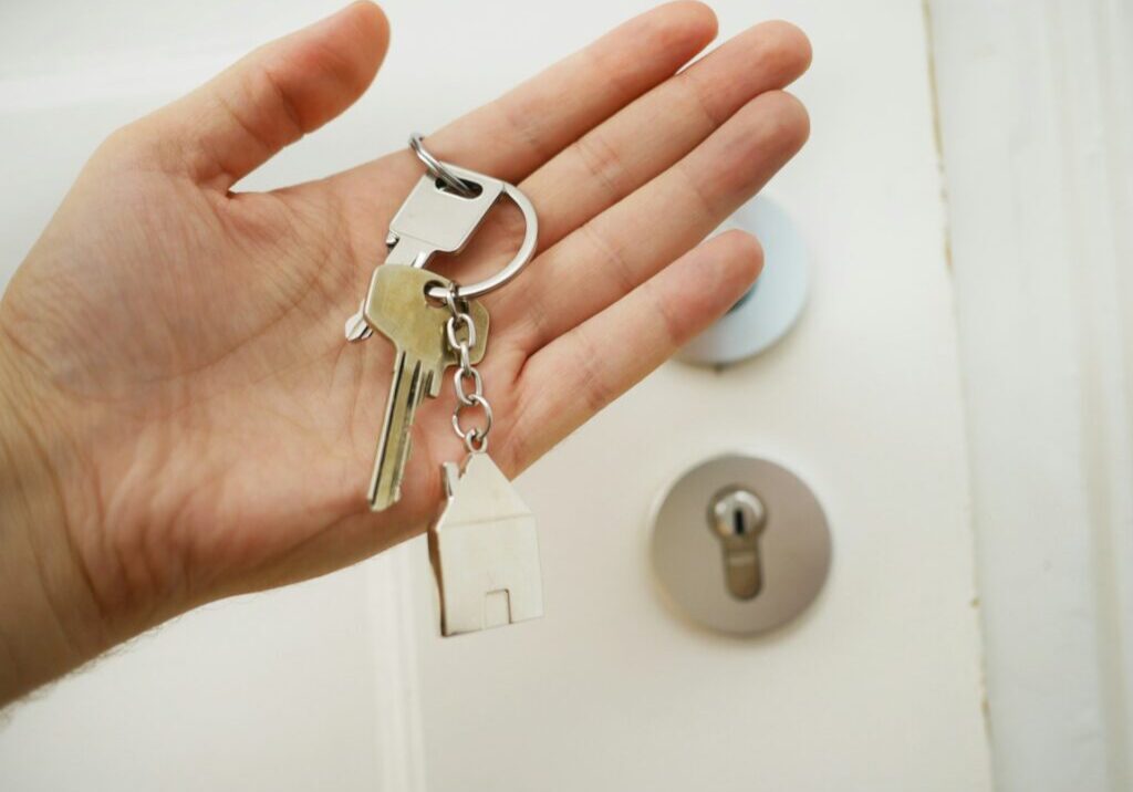 Hand holding keys in front of a door lock.