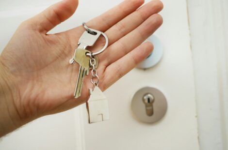 Hand holding keys in front of a door lock.